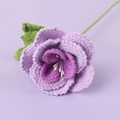 Detailed close-up of handmade crochet purple rose with intricate knit petals and green leaf - French Rose / Purple
