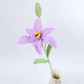 Detail einer handgehäkelten lila Lilie mit grünen Blättern in weißer Keramikvase - Lila (mit Knospe)