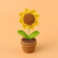 Handmade crochet sunflower potted plant in bright yellow on a warm orange background - 4-ringed Pointed Sunflower Potted Plant (small Mini Yarn Pot)