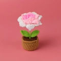 Gros plan d'un tournesol au crochet fait main avec pétales roses et pot en laine marron - Paillettes dégradées