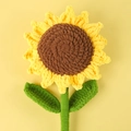 Handmade crochet sunflower with soft yellow petals and green leaves on a yellow background - Ordinary Sunflower