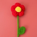Detail van een handgemaakte gehaakte pofbloem van zacht rood en geel garen als cadeau - Rood