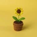 Detail einer handgehäkelten Sonnenblume im braunen Topf auf gelbem Hintergrund - Einzelner Sonnenblumenkopf (Kleiner Mini-Wolltopf)