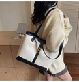 Detalle de un bolso tote grande en cuero PU beige con asas negras y cierre de giro dorado - Negro