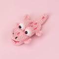 Nahaufnahme einer gehäkelten rosa Krokodil-Haarklammer mit 3D-Augen und Webstruktur - Rosa