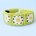 Detail eines handgestrickten hellgrünen Stirnbands mit Gänseblümchen-Mustern und schwarzem Futter - Sonnenblume Stirnband - Knospengrün
