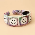 Detail showing hand-knitted hairband with white crochet squares and black smiley face patterns - Smile Face Headband - Purple