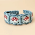 Detail of hand-knitted blue headband featuring red mushroom embroidery and soft crochet texture - Mushroom Headband - Blue