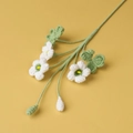 Close-up of handmade crochet white flowers with green buds and leaves on yellow background - 3-Head Shamrock Flower Branch / White