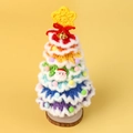 Detail eines handgehäkelten Regenbogen-Weihnachtsbaums mit Glocke auf Holzsockel - Regenbogen