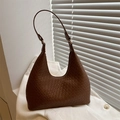 Classic brown woven leather hobo bag with adjustable strap in minimalist studio setting - Tan
