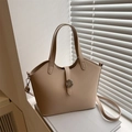 Chic beige tote bag with round metal buckle and adjustable strap in minimalist setting - Khaki