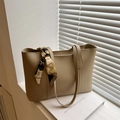 Minimalistische beige Tragetasche mit dekorativem Schal auf Fensterbank im Sonnenlicht - Khaki