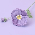Detailed view of hand-knitted purple pansy flower with green stem and leaf - Gradient Purple
