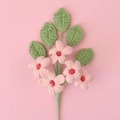 Macro view of five pink handmade crochet flowers with green leaves and knitted texture - Pink