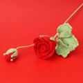 Detail einer handgehäkelten roten Rose mit feiner Stricktextur und grünen Blättern - Rot (Rosenzweig)