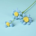 Close-up of handmade crochet blue daisies showing intricate yarn texture and yellow cores - Blue