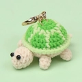 Close-up of handmade crochet turtle keychain with green yarn shell and golden metal clasp - Gradient Green