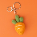 Macro shot of handmade crochet carrot keychain with orange yarn and metal clasp - Orange Carrot