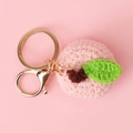 Detail of a handmade crochet peach keychain with pink yarn and golden metal ring - Pink Peach