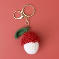 Macro detail of a handmade crochet lychee keychain with gold metal clasp on coral background - Crocheted Red Lychee Keychain (lobster Clasp)