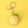 Close-up of handmade crochet orange fruit slice keychain with golden metal clasp - Yellow Orange Slice