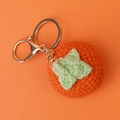 Close-up of handmade crochet persimmon bag charm with orange yarn and golden keyring - Orange Persimmon