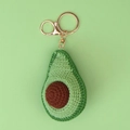 Macro shot of handmade crochet avocado keychain with detailed golden metal hardware - Green Avocado