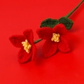 Gros plan de fleurs rouges crochetées à la main avec étamines jaunes et feuilles vertes - Rouge