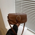 Retro bruine crossbodytas met gouden hoefijzer gesp op een minimalistische achtergrond - Bruin