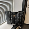 Sac fourre-tout noir classique avec motif d'ours et boucle dorée dans une pièce moderne - Noir