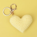 Close-up of a handmade yellow crochet heart keychain with a golden metal clasp - Yellow