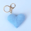 Macro shot of light blue handmade crochet heart keychain with golden metal clasp - Blue