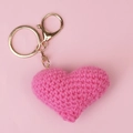 Close-up of pink handmade crochet heart keychain with golden metal ring and lobster clasp - Rose Red