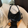 Elegante borsa nera a tracolla con fiocco e logo argento su sfondo blazer beige neutro - Nero