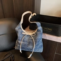 Borsa hobo in denim blu con fiocco beige e dettagli di perline su sedia nera - Blu Notte e Bianco