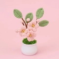 Macro detail of hand-crocheted pink cherry blossom plant with white pot on pink background - Peach Blossom Potted (White Pot)