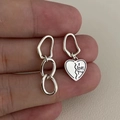 Vista macro di orecchini asimmetrici in argento s925 con pendente a cuore e incisione - Orecchini a cuore asimmetrici