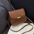 Brown vintage faux leather crossbody bag with golden lock on book background - Brown