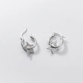 Dettaglio degli orecchini a stella in argento S925 con texture martellata su grigio - Oro Bianco