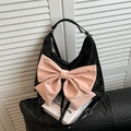 Schicke schwarze Schultertasche mit großer rosa Schleife auf samtiger Oberfläche - Schwarz