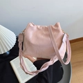 Pink glossy bucket bag with woven handle and gold hardware in a stylish room setting - Pink