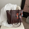 Dunkelbraune matte Leder-Tote-Bag mit dekorativem Seidenschal auf modernem Stuhl - Dunkelbraun