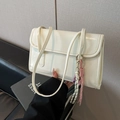 Minimalist white leather shoulder bag with a decorative woven cord charm and dual straps - White Bag Style