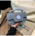 Detailed macro view of mini blue denim crossbody bag with round buckle and pearl accents - Blue