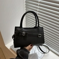 Elegant black matte leather handbag featuring a decorative bow and handle, held by hand - Black
