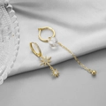 Dettaglio di orecchini dorati asimmetrici con pendenti a stella e perline di vetro - Orecchini a Cerchio con Nappa a Stella Asimmetrici