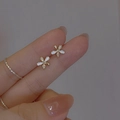 Detailed macro view of delicate gold flower earrings with white enamel and micro diamonds - Small Flower Stud Earrings