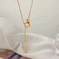 Macro shot of 18K gold geometric Y-shaped necklace with hollow square pendants on white silk - Gold