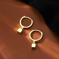 Vue détaillée des boucles d'oreilles dorées cubes géométriques sur cuir et soie - Huggie Cube Géométrique - Or